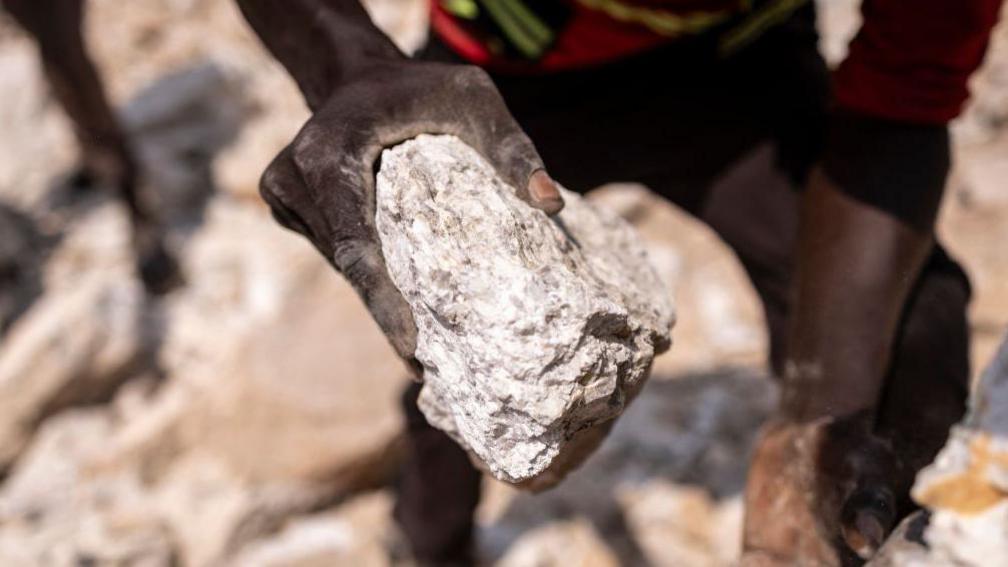 A miner holding a rock that contains lithium at a mine in Nigeria