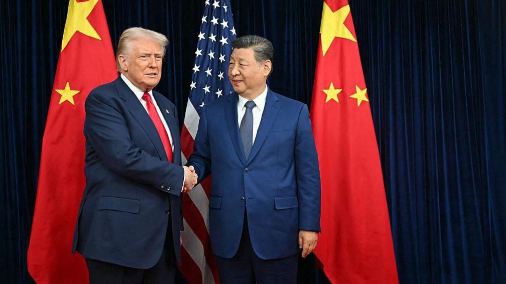 US President Donald Trump (L) and China's President Xi Jinping shake hands as they arrive for talks at the Gimhae Air Base, located next to the Gimhae International Airport in Busan on October 30, 2025.