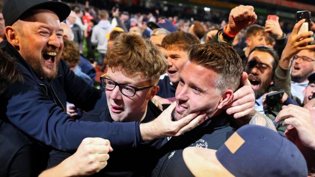 Rob Edwards crowded by fans at Luton Town Football Club