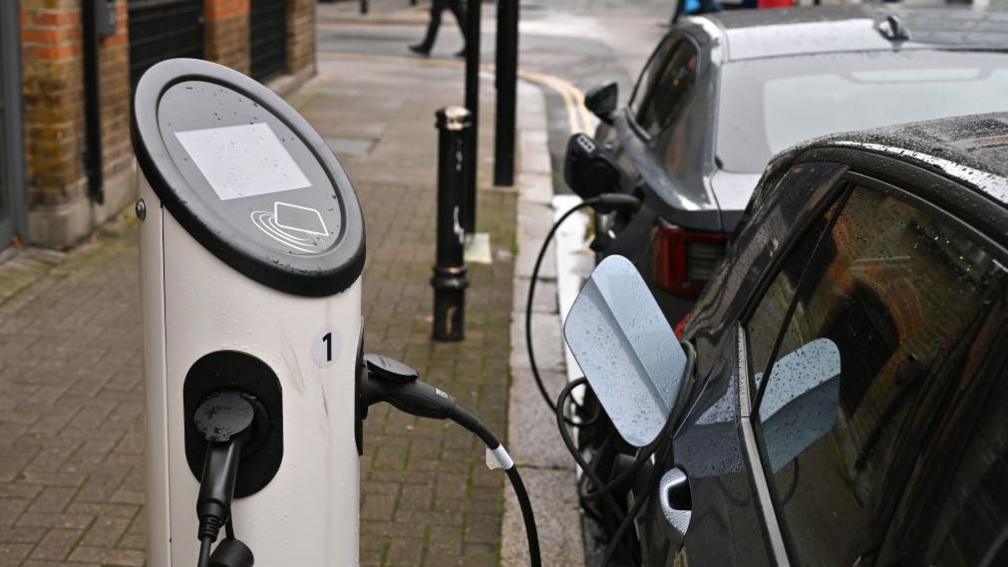 Cars parked on a street using a public charging point