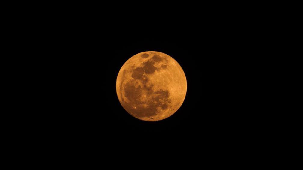 An orange moon in a dark sky