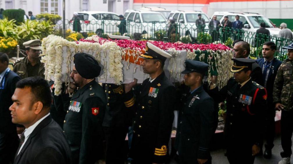 Officers carrying a coffin draped in flowers and an Indian flag