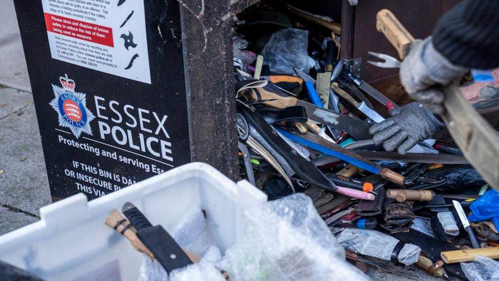 An Essex Police knife drop off box with many different types of knives inside.