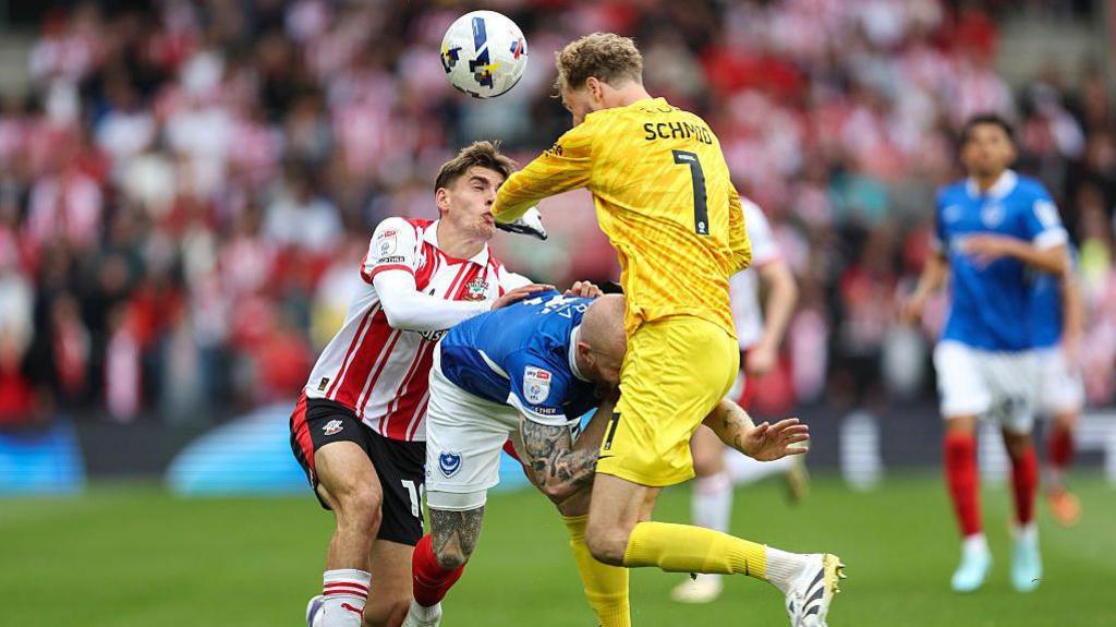 Tom Fellows of Southampton shoves Connor Ogilvie of Portsmouth forward as Portsmouth goalkeeper Nico Schmid comes out to head the ball, leading them to collide 