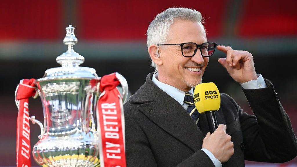 BBC presenter Gary Lineker looks on with the FA Cup trophy after the Emirates FA Cup Semi Final match 