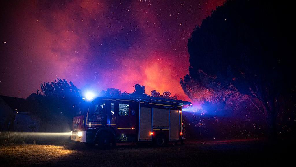 Firefighters move in a fire truck as a forest burns close to a residential area during a wildfire near Lege-Cap-Ferret, southwestern France.