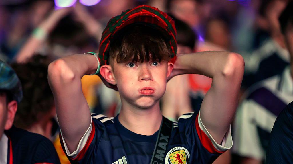 Yong Scotland fan with hands on head.