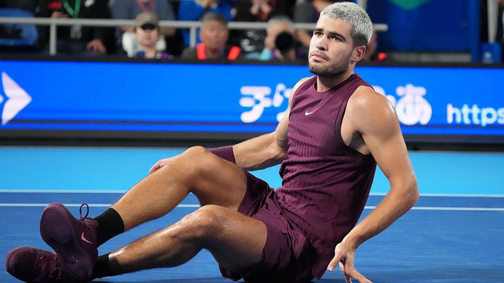 Carlos Alcaraz sits on the court after hurting his ankle 