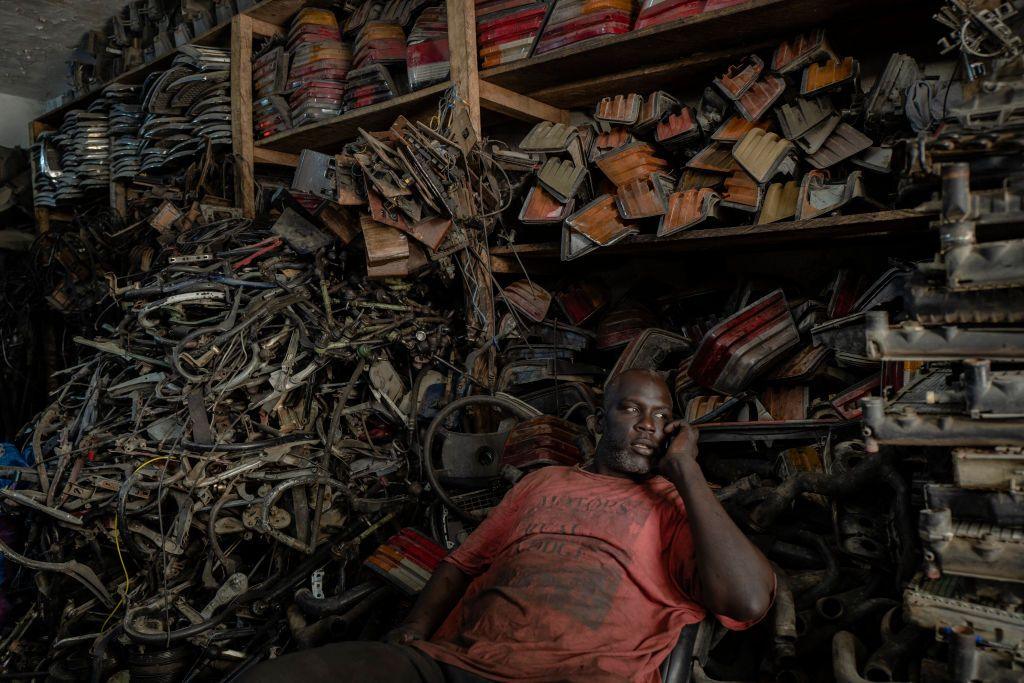 A man sits in front of Mercedes spare parts piled high in a garage. The Mercedes 190 is one of the most imported cars in Mauritania because of its easy-to-repair mechanics and its resistance to high temperatures, according to the AFP news agency.