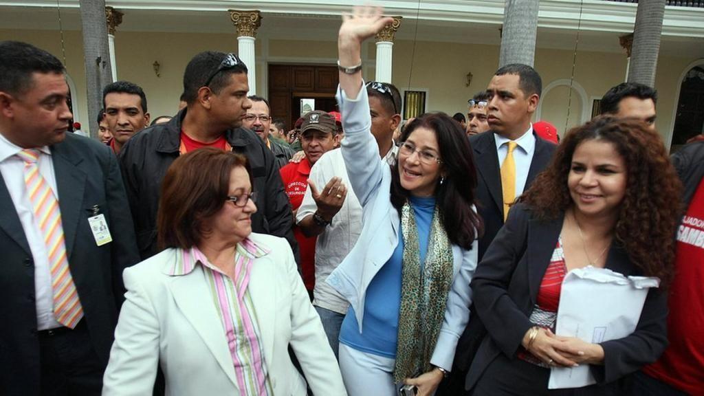 Flores with colleagues waving to a crowd