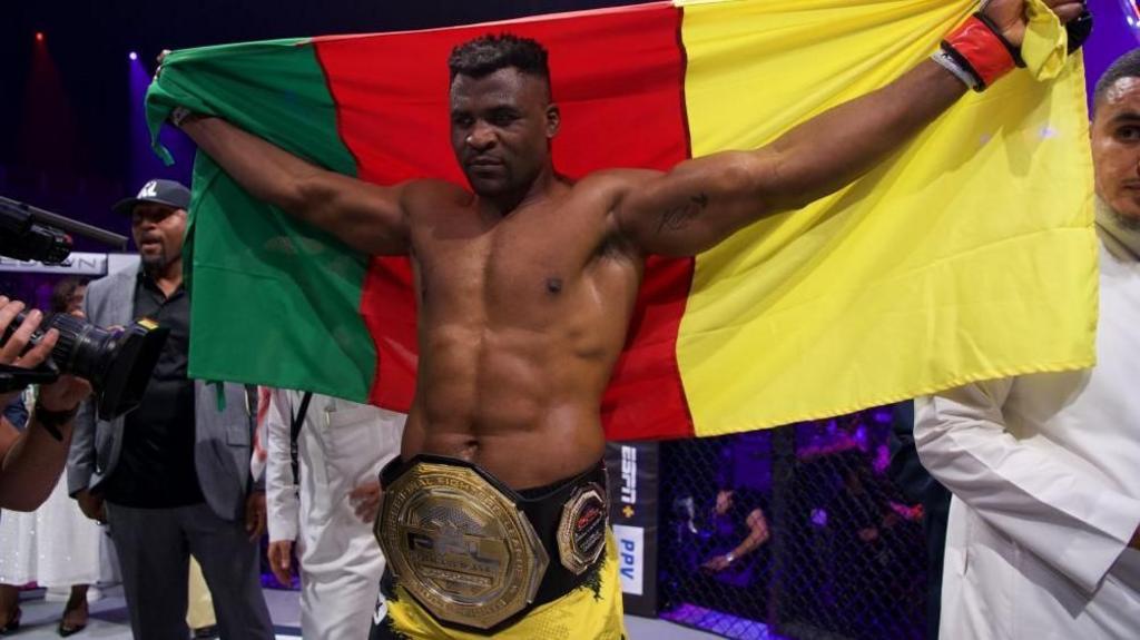 Francis Ngannou with the Cameroon flag and a PFL belt around his waist