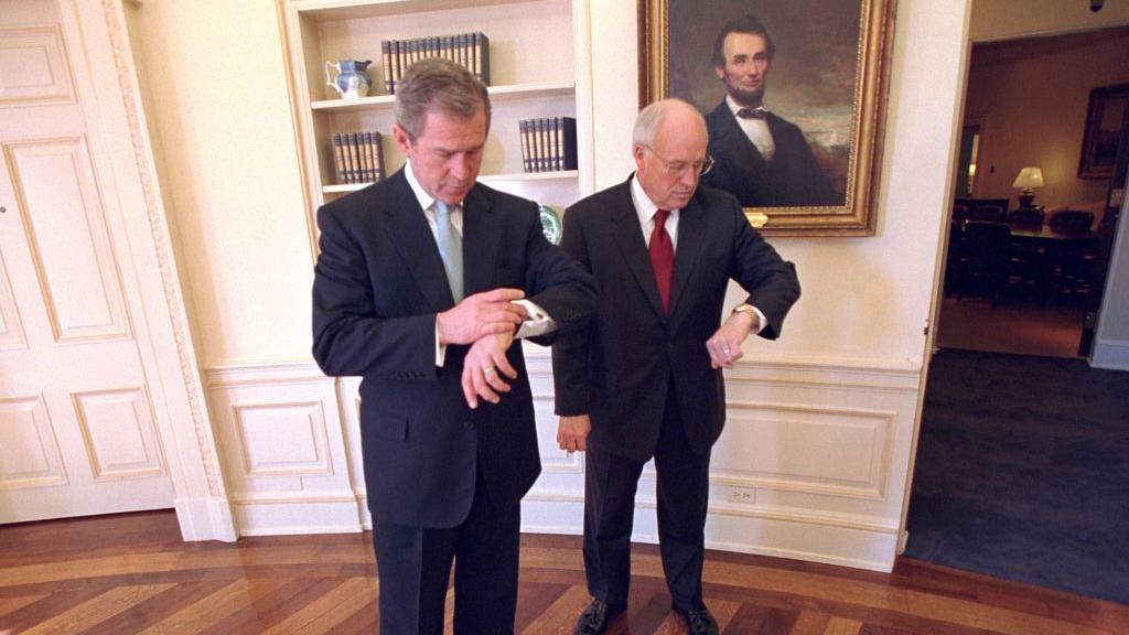 George W Bush and Dick Cheney check their watches in the Oval Office
