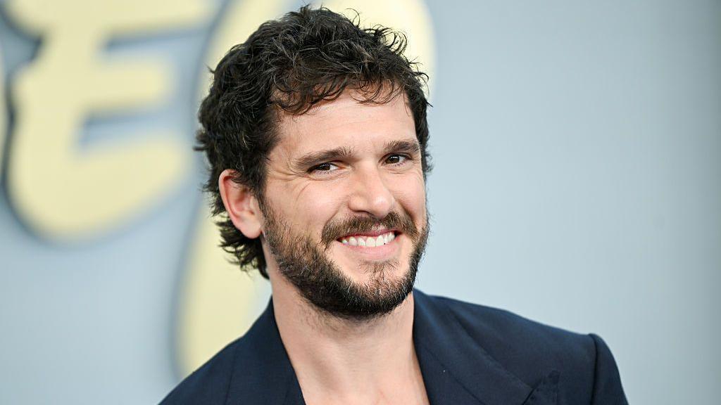 Kit Harrington seen smiling on the red carpet in a blue blazer 