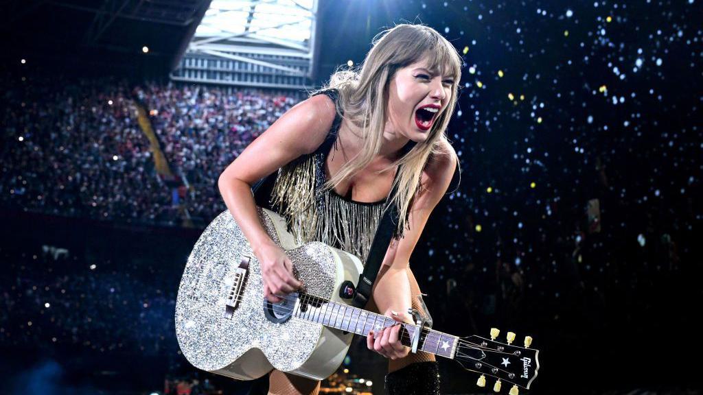 Taylor Swift canta mientras toca la guitarra en el escenario del Principality Stadium