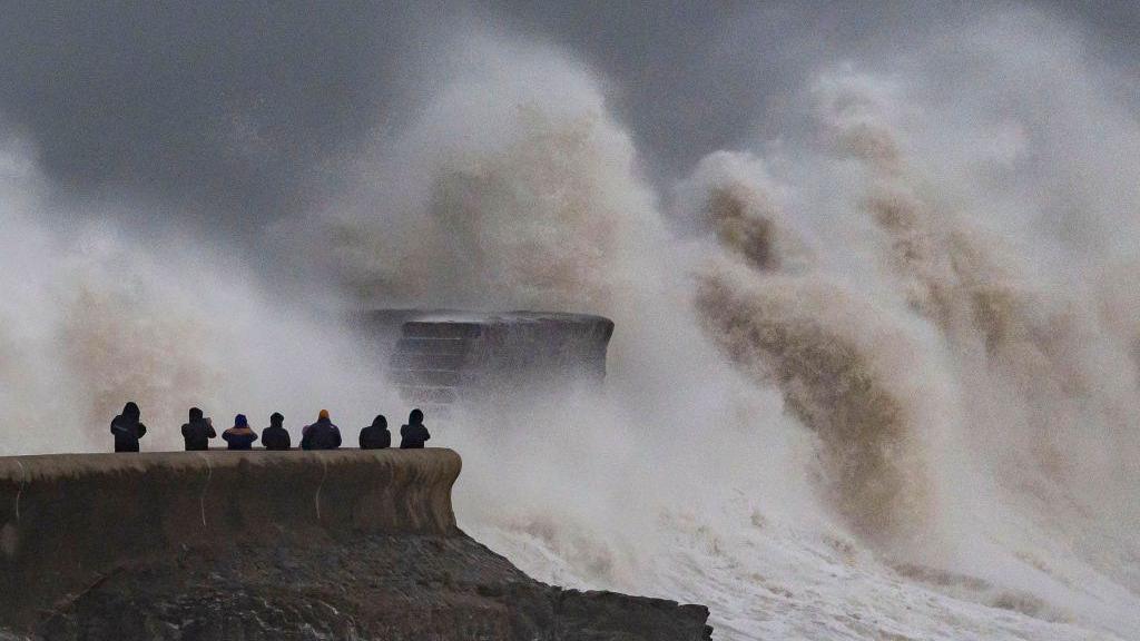 A huge wave shoots up a sea wall next to a light house on the Bristol channel at Porthcawl