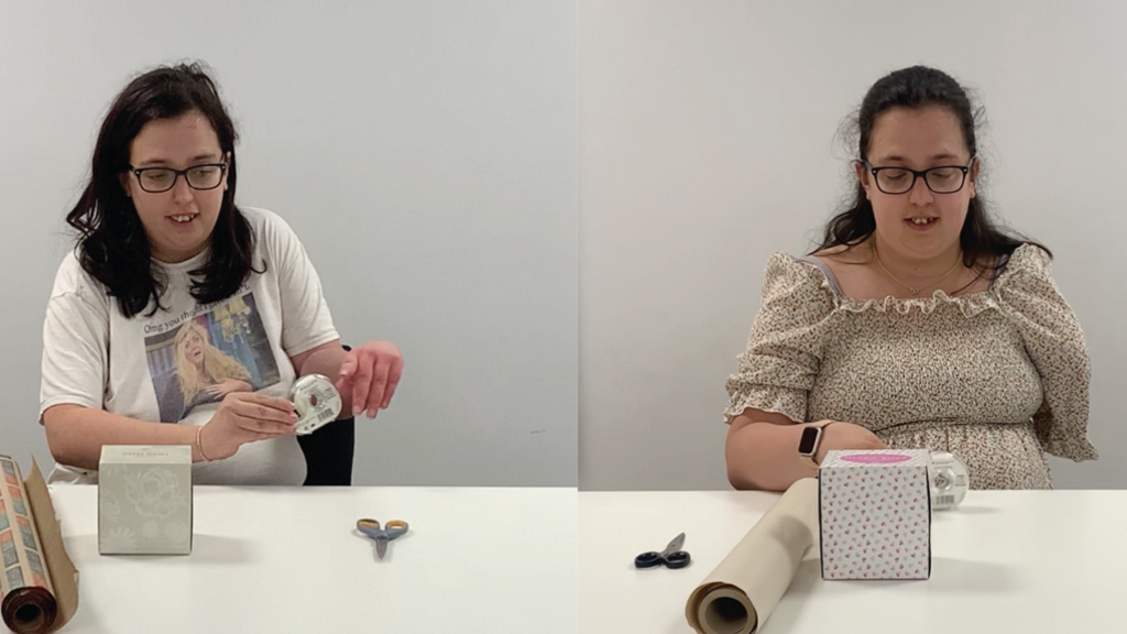 Composite side by side images of Ms Wheldon before and after her amputation. She is sitting at a table in the same white room in both photos. In both images she has a pair of scissors, Sellotape, wrapping paper and a box - a task she has been set as part of the study. The image on the left is before the amputation of her arm. She has medium length dark hair and is wearing a white top. In the right image she has slightly longer hair, is wearing a yellow dress, and has had her amputation.