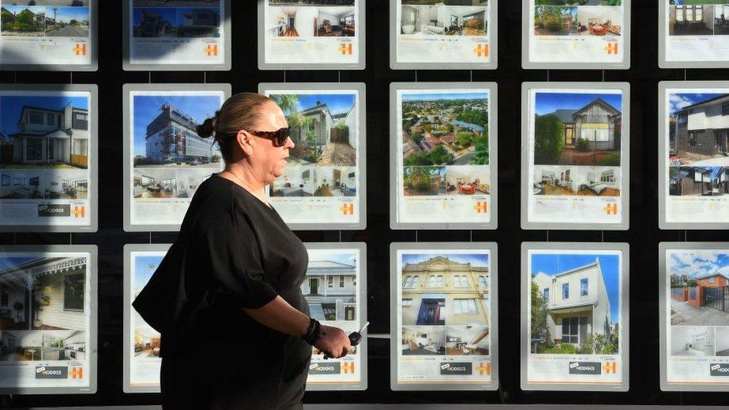 Woman walking by estate agent window