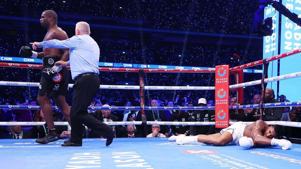 Anthony Joshua is on the canvas as Dubois is ushered away by the referee