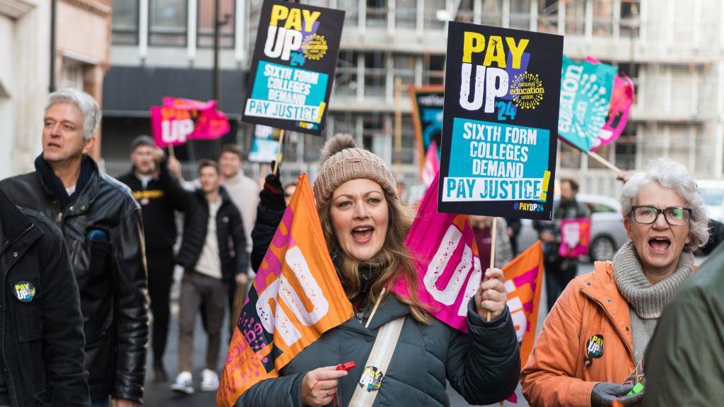 A woman holds up a sign saying "pay up".