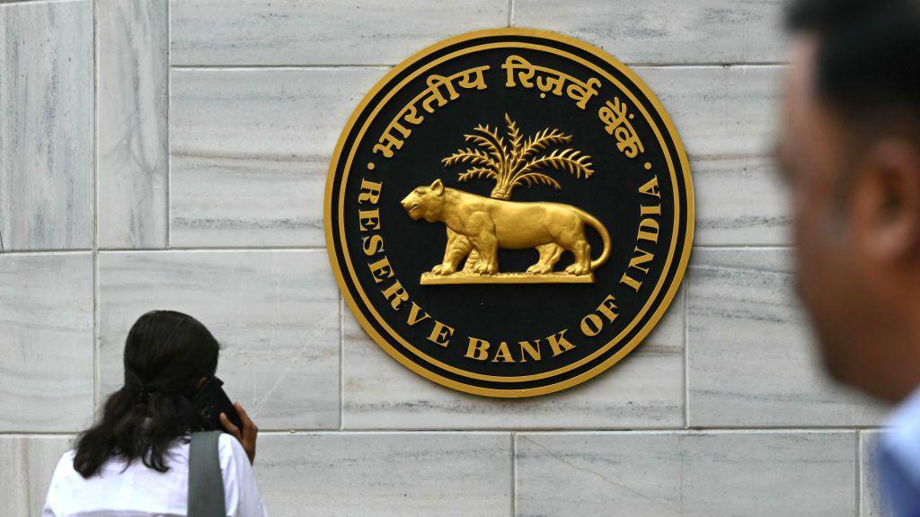 Pedestrians walk past the Reserve Bank of India (RBI) signage outside its headquarters ahead of the monetary policy press conference in Mumbai on December 6, 2024