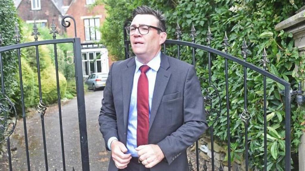 Burnham stands in front of the gates of his home