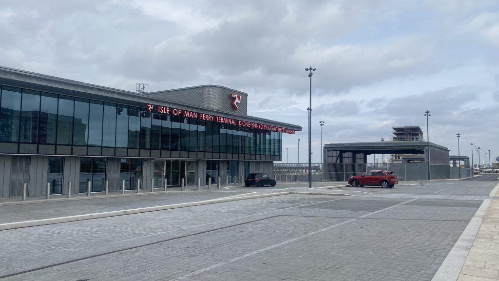 The terminal's car park with two cars parked in it below a grey sky. 