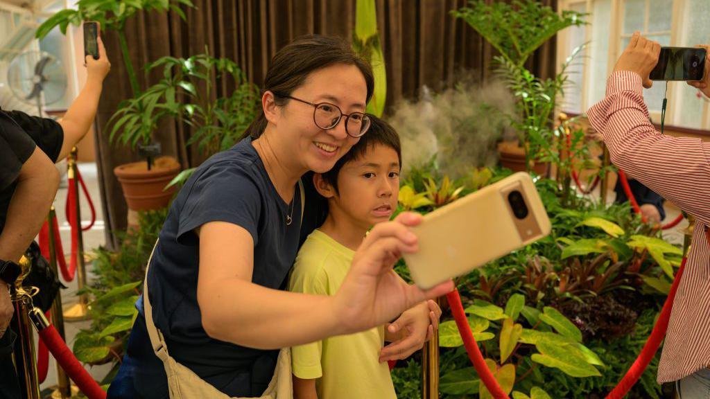 A woman and a boy taking a selfie near the corpse flower