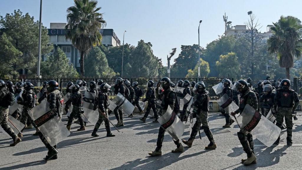 Paramilitary soldiers march along a street leading to the Red Zone area during a protest by the supporters of the Pakistan Tehreek-e-Insaf (PTI) party