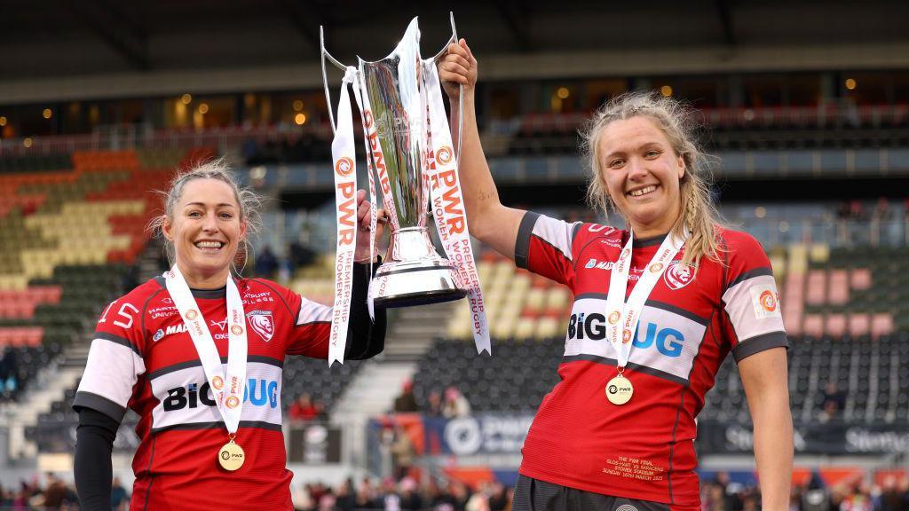 Natasha 'Mo' Hunt and Zoe Aldcroft of Gloucester-Hartpury holding the PWR trophy up 