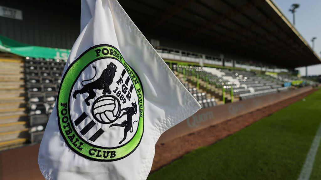 A white corner flag with a Forest Green Rovers crest flying next to a stand