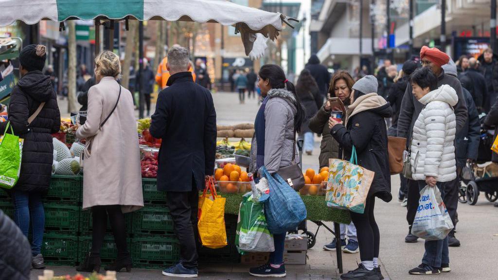 Shoppers queue at a fruit and vegetable stall in Bexleyheath, Greater London, UK, on Monday, Dec. 18, 2023.