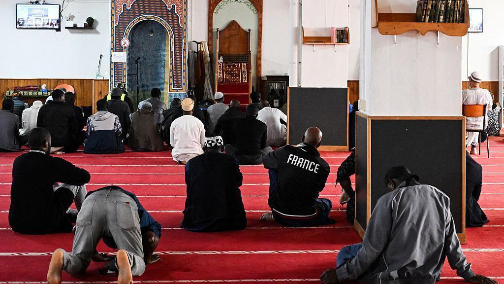 Men sit down to pray at a mosque in Paris