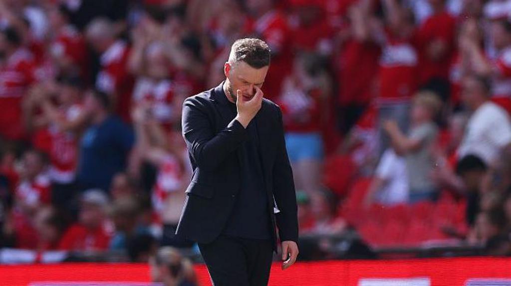 Kim Hellberg looking down at the floor, while scratching his face with his right hand at Wembley