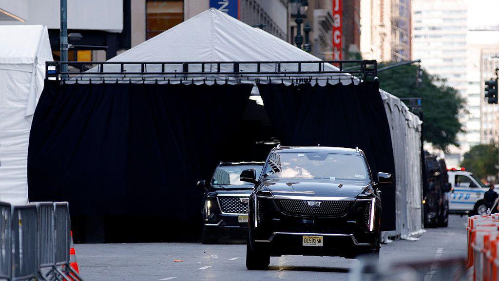 Two blacked out SUV cars pulling out of a tent outside Madison Square Garden.