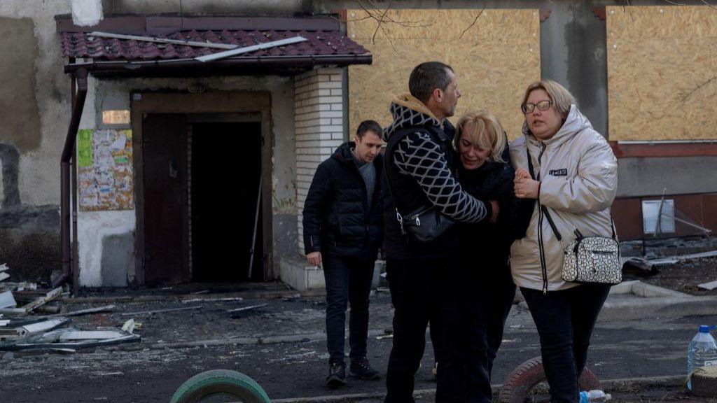 People hug a crying woman near a damaged residential building following a strike in Dobropillia, Donetsk region