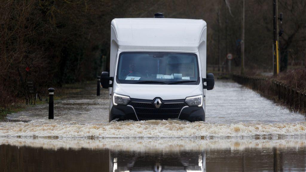 A white van wades through flood water