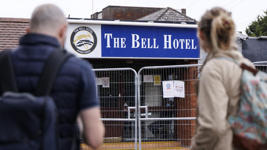 Two people stand outside the Bell Hotel