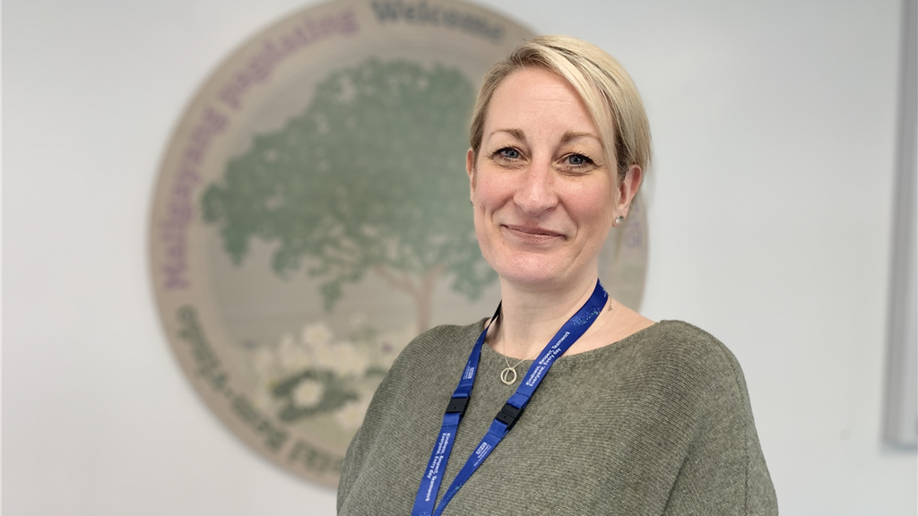 Women with blonde hair and blue lanyard smiling at the camera