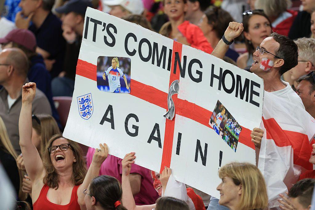 England fans with a banner reading "It's coming home, again" during the semi-Final match between England and Italy at Stade de Geneve on July 22, 2025 in Geneva, Switzerland.