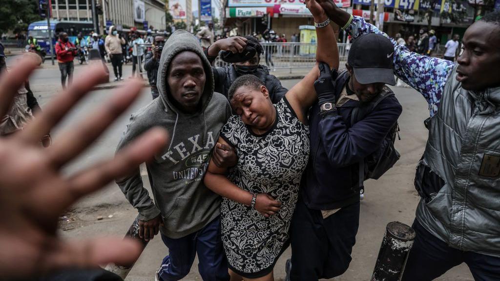 A woman (C) suffering from tear gas inhalation is helped away by during renewed demonstrations in Nairobi on July 16, 2024. 