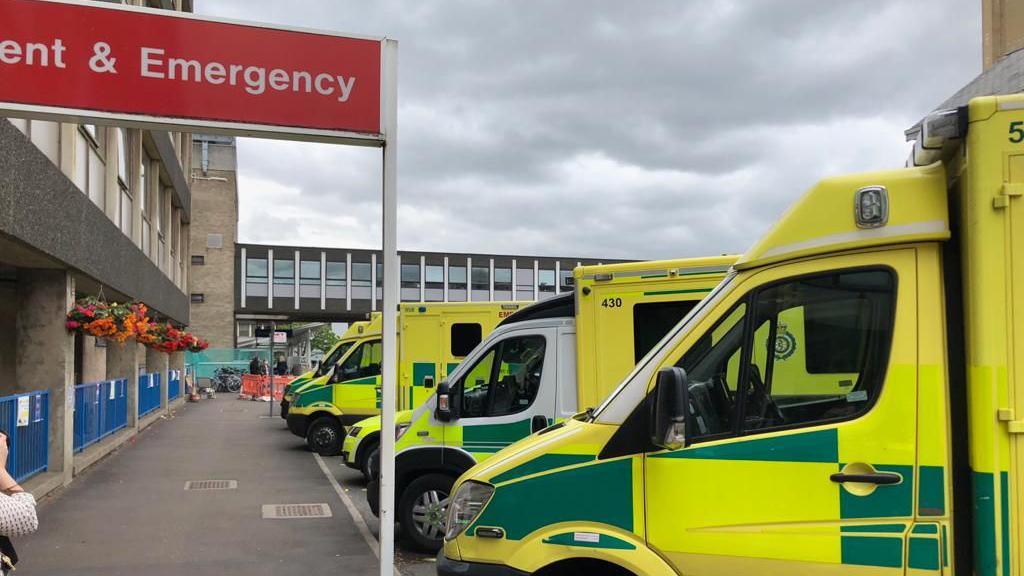 Row of yellow and green ambulances outside and emergency unit building