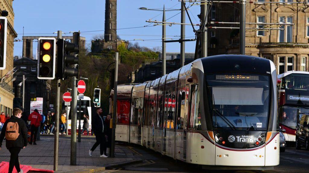A tram in front of the Balmoral Hotel in Edinburgh on a sunny day.