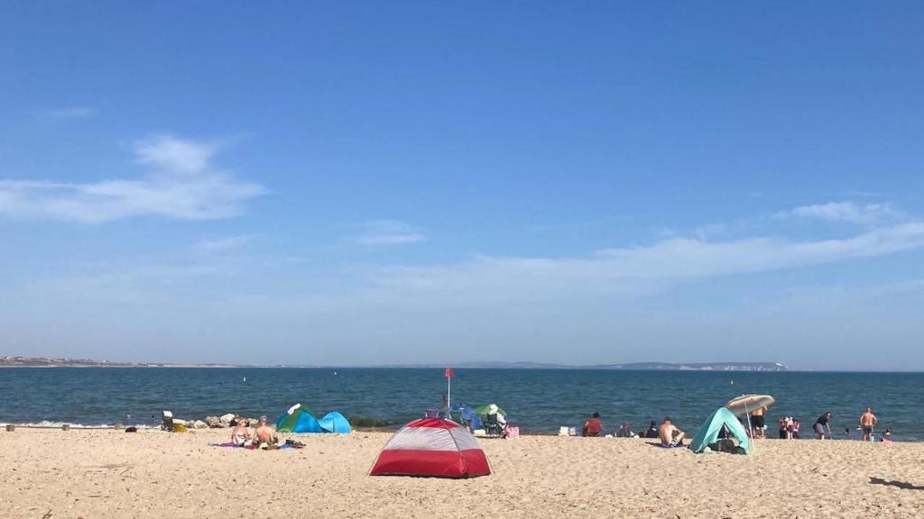 A beach scene with a tent and sunshade