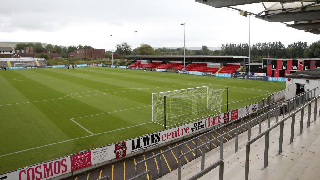 An overhead view of a football pitch, with a cloudy sky in the background