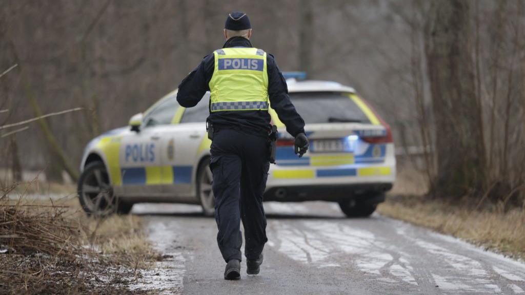 A police officers walks towards a police vehicle near the Risbergska School in Orebro, Sweden, on February 4, 2025, following reports of a serious violent crime. 