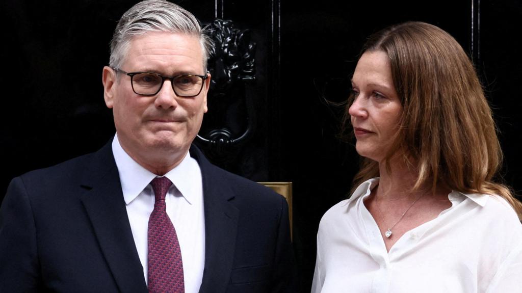 Keir Starmer and his wife stand outside the front door of 10 Downing Street