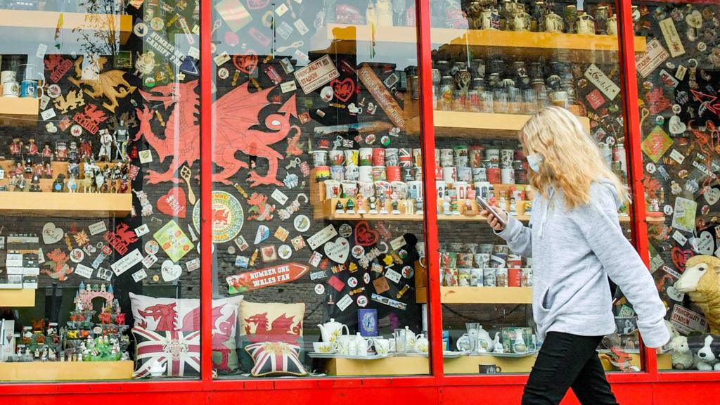 A woman wears a face covering as she walks past a shop in Cardiff, 28 September 2020