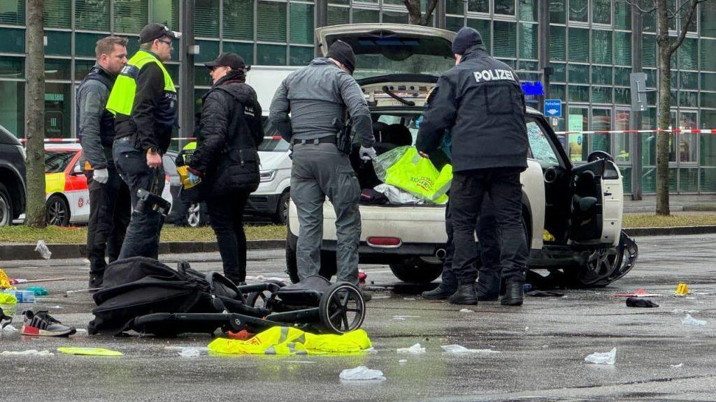 A child's buggy lies on the ground beside a Mini Cooper car used to attack a crowd in Munich