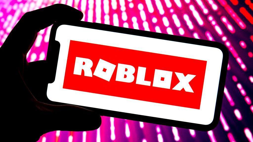 A Roblox logo is displayed on the screen of a smartphone