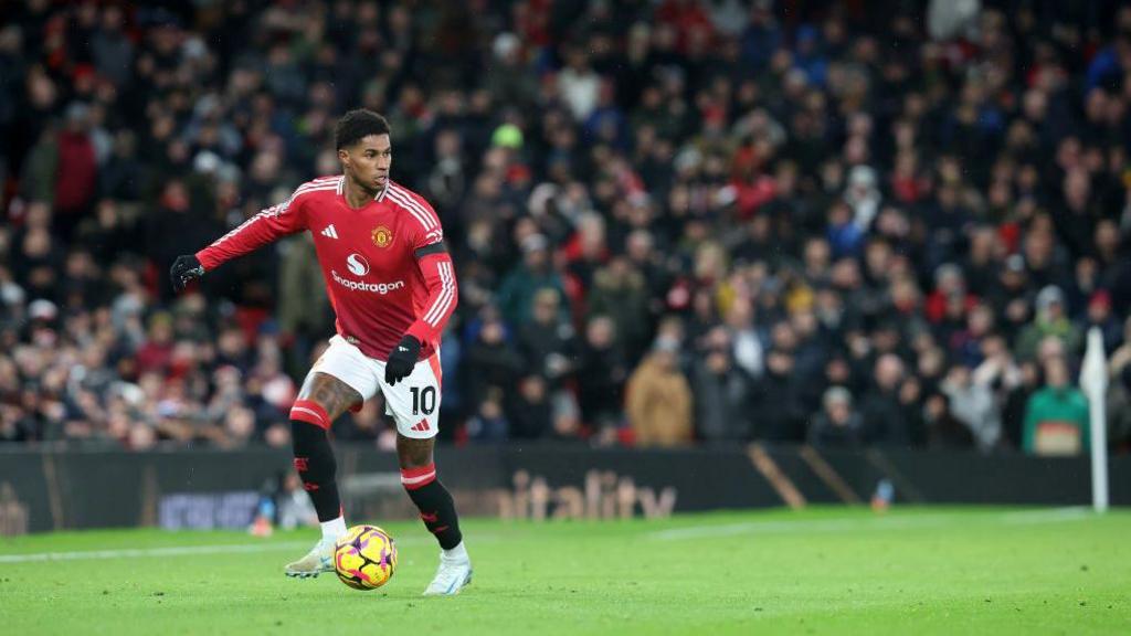 A gloved Marcus Rashford has possession and looks to progress forward for United